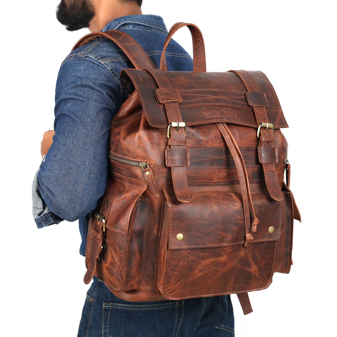Brown leather backpack worn by a person on a white background
