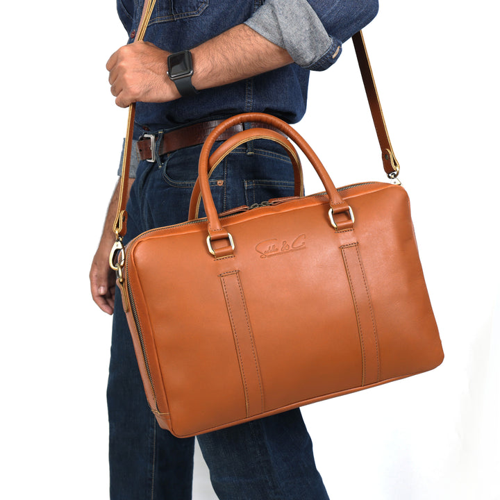 Person holding a brown leather briefcase with a visible brand logo on a white background