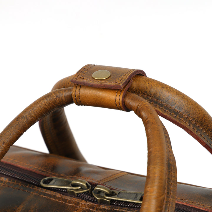 Close-up of a brown leather bag with gold zipper and clasp on a white background
