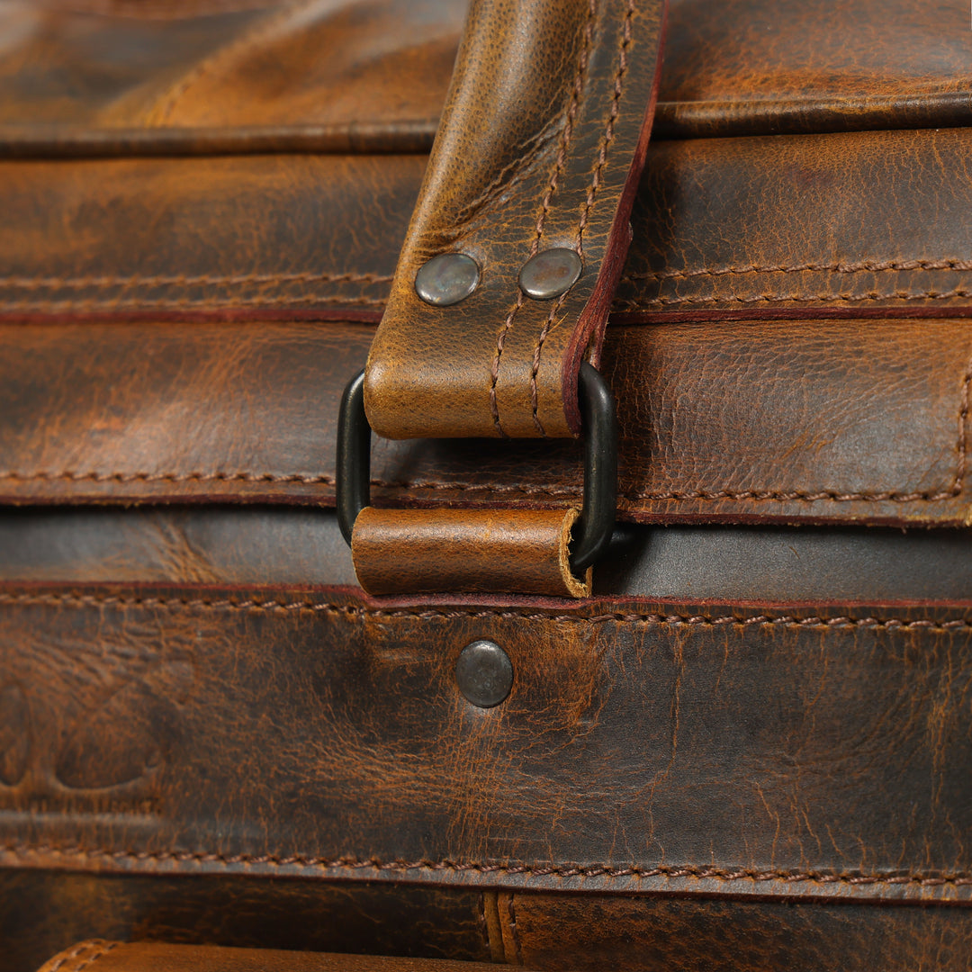 Close-up of a brown leather bag with strap and stitching details
