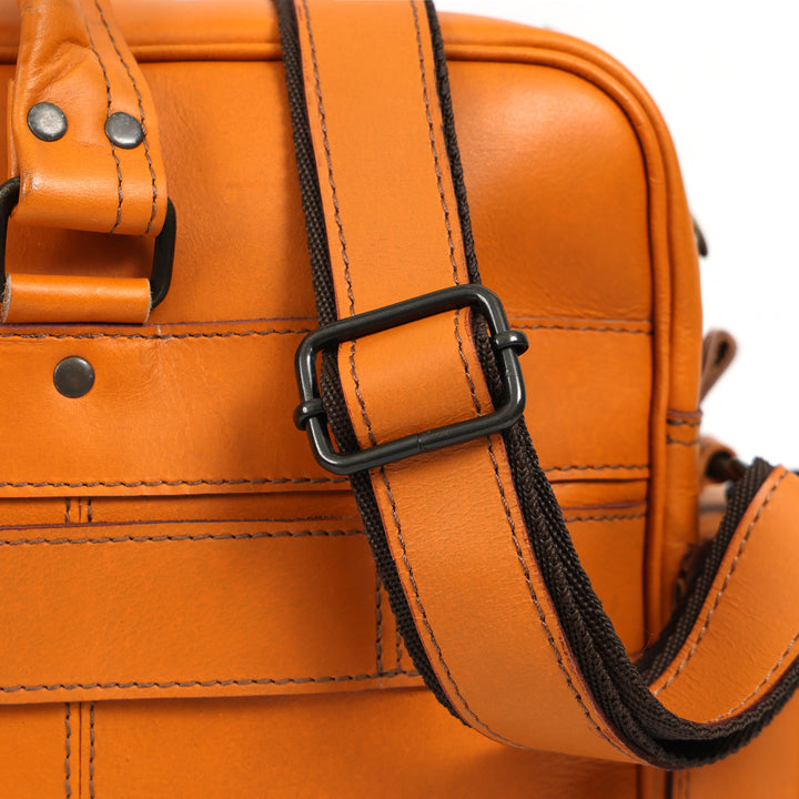 Close-up of an orange leather bag with a black strap on a white background