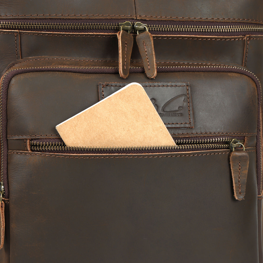 Close-up of a brown leather bag with a zipper, featuring a brand logo.