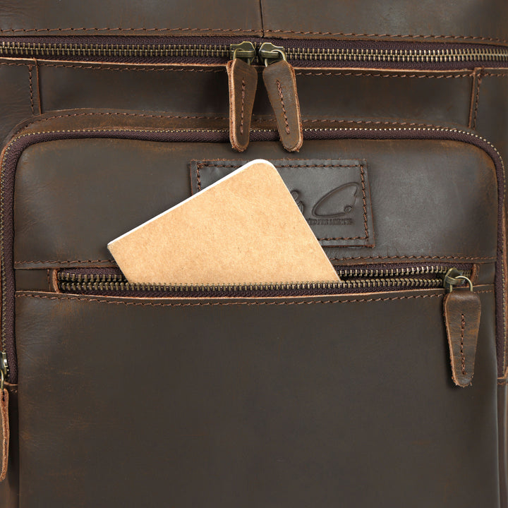 Close-up of a brown leather bag with a zipper, featuring a brand logo.