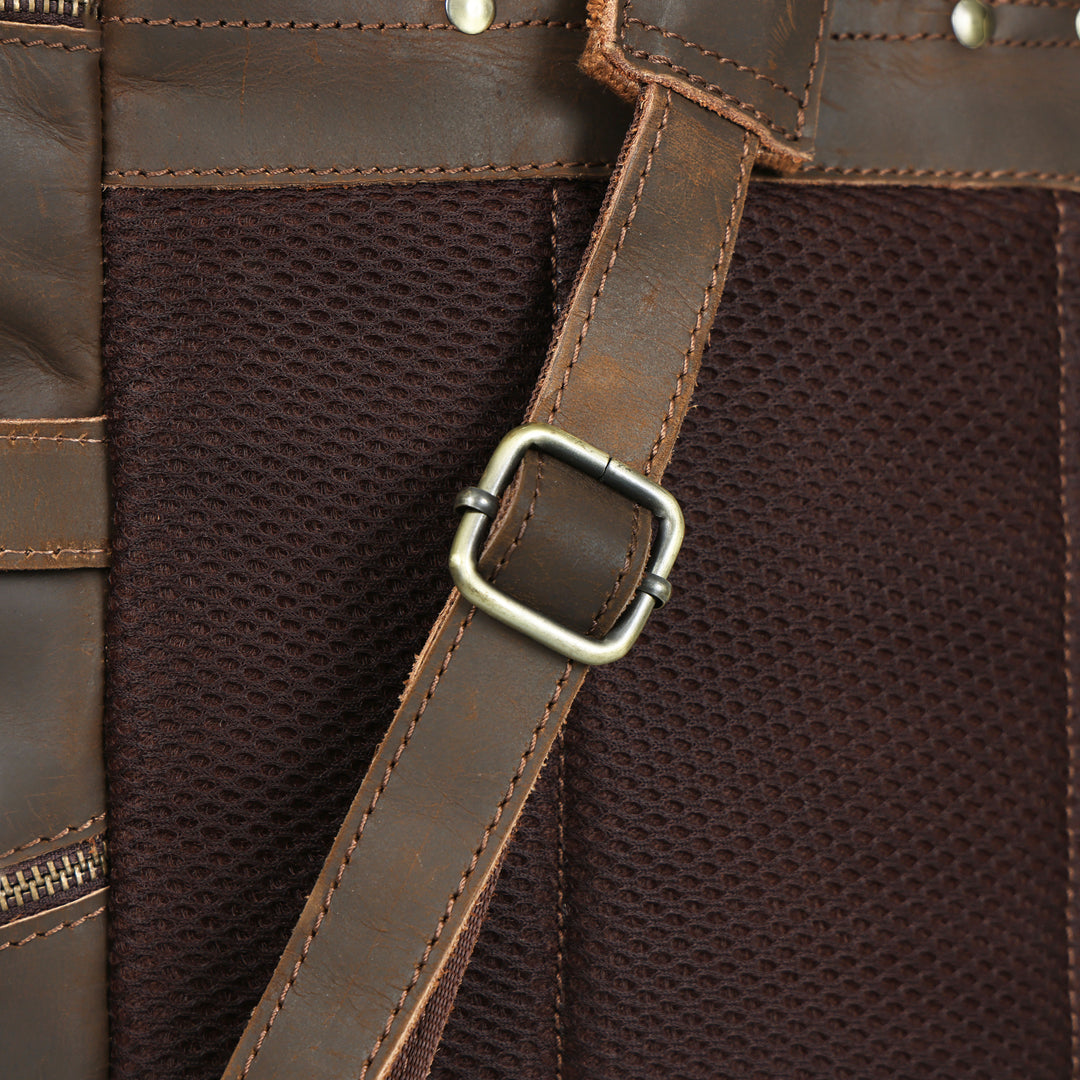 Close-up of a brown leather bag with a strap and buckle