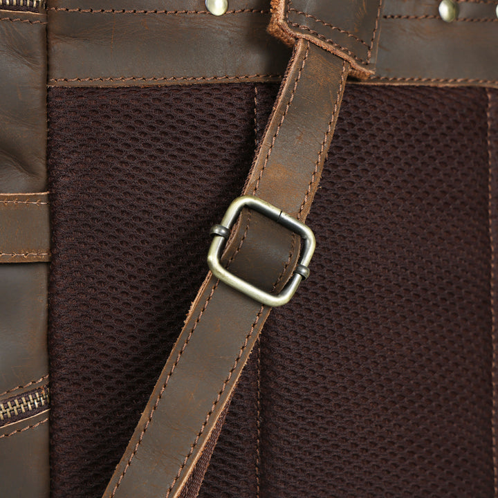 Close-up of a brown leather bag with a strap and buckle