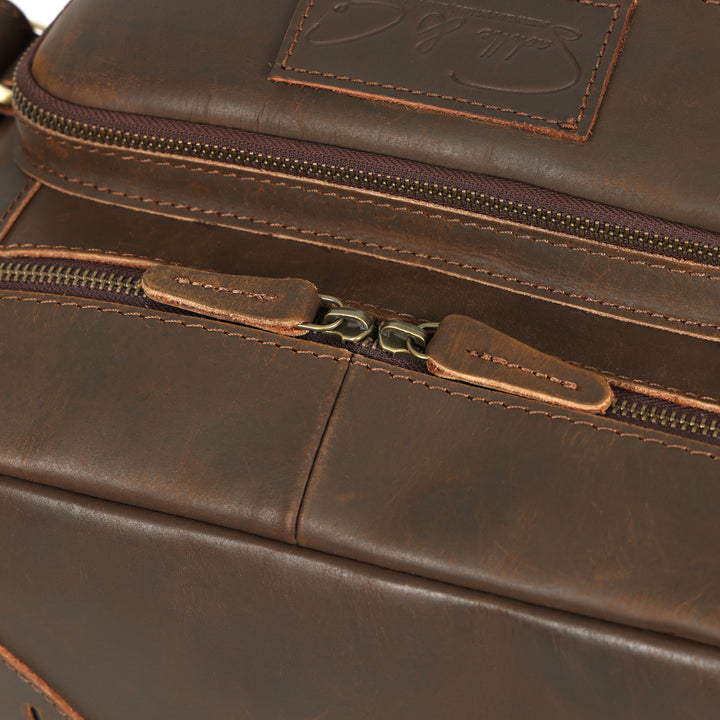 Close-up of a brown leather bag with zippers and a brand logo.
