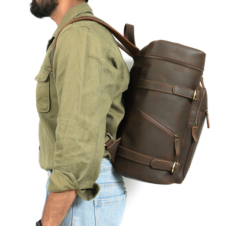 Person wearing a large brown leather backpack on a white background
