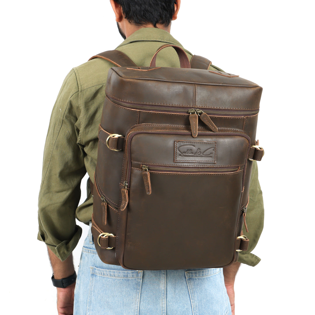 Man wearing a brown leather backpack with visible brand logo on a white background