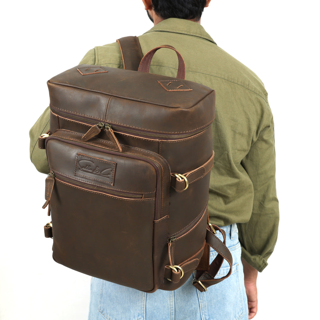 Brown leather backpack worn by a person on a white background